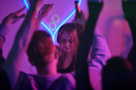 pretty_girl_with_long_blond_hair_standing_by_counter_with_turntables_while_mixing_music_disco_dancing_enjoying_home_party_with_friends